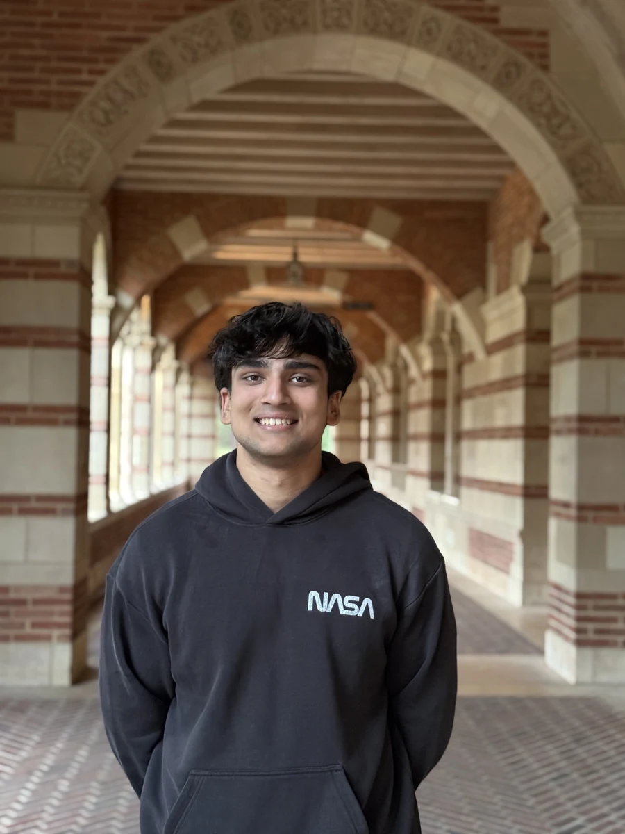 Ishaan Saraswat at UCLA, standing under the brick arches